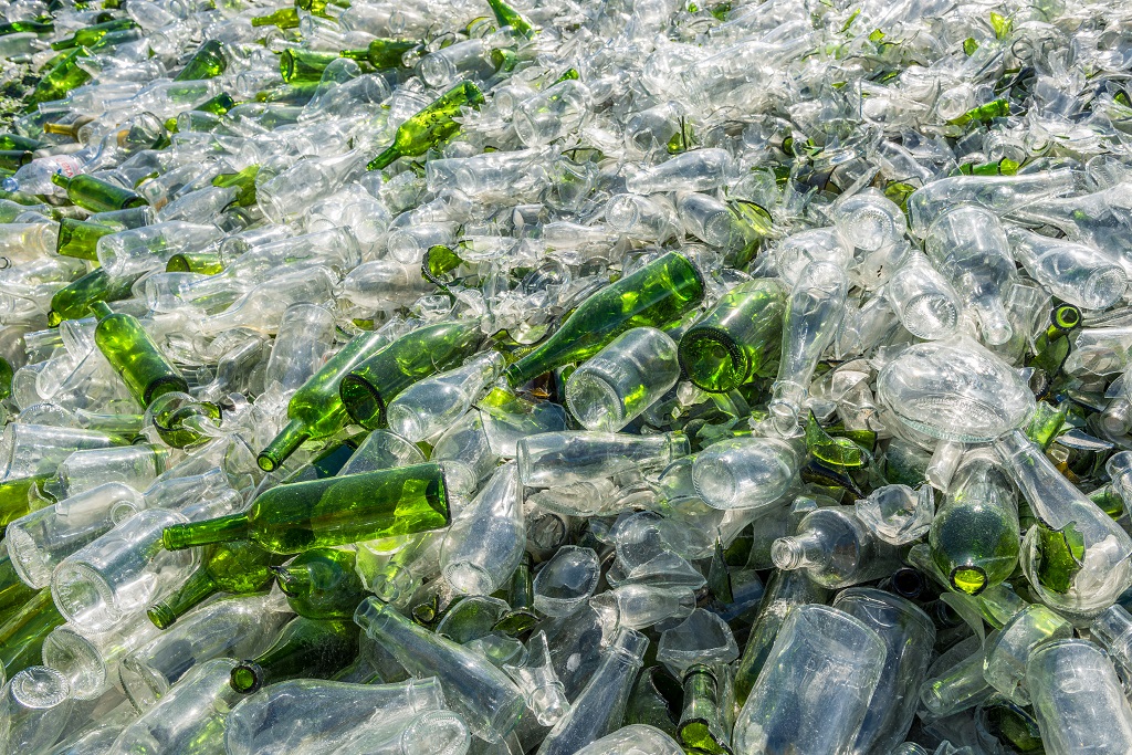 Zużyte butelki szklane z zielonego i białego szkła w dużej ilości w zakładzie recyklingu
