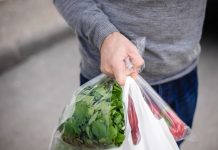 Hiszpania. Po wprowadzeniu opłat za foliowe torby ich użycie spadło o 40% Male carrying bag in his hand after shopping. Closeup of bag full of fruits and vegetables.