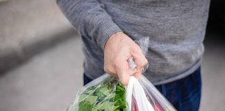Male carrying bag in his hand after shopping. Closeup of bag full of fruits and vegetables.