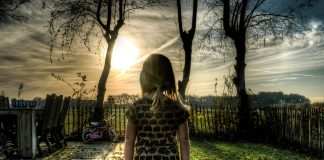 Dziewczynka stojąca przed płotem na wsi