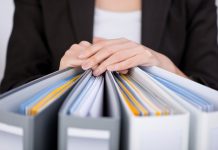 Midsection of businesswoman with binders at office