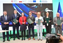 W podpisaniu umowy w dniu 13 maja 2026 r. udział wzięli (na zdjęciu od lewej): Mirosław Suchoń, Przewodniczący Komisji Infrastruktury, Cyprian Gronkiewicz, Prezes ElectroMobility Poland S.A., Eliza Zeidler, Sekretarz Stanu w Ministerstwie Aktywów Państwowych, Wojciech Balczun, Minister Aktywów Państwowych, Paulina Hennig-Kloska, Minister Klimatu i Środowiska, Dorota Zawadzka-Stępniak, Prezes Zarządu NFOŚiGW, Paweł Augustyn, Zastępca Prezesa Zarządu NFOŚiGW.